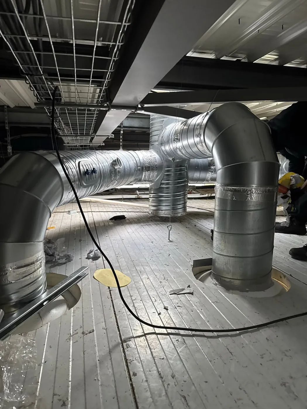 Réseau de conduits d'extraction galvanisés en cours d'installation en faux plafond